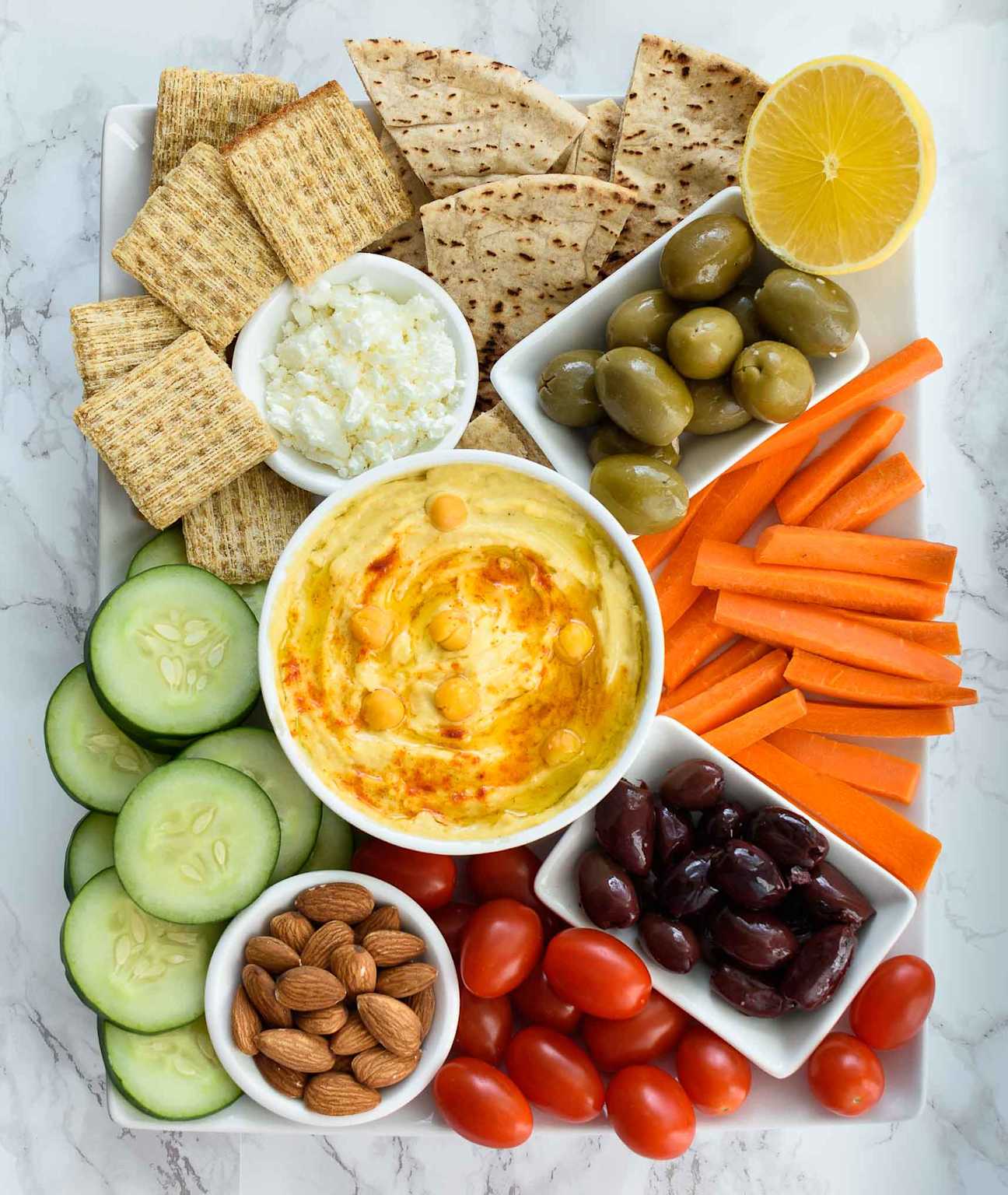 Healthy hummus platter with bread, vegetables, olives, and crackers